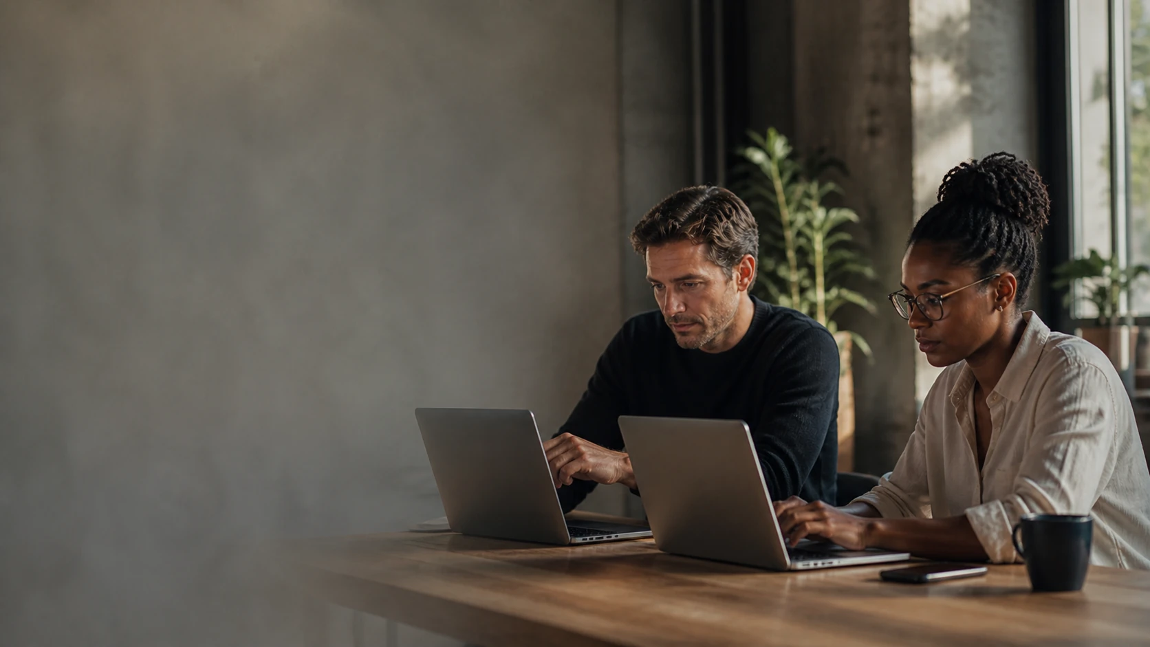 Duas pessoas trabalham em conjunto nos seus computadores num escritório de startup.